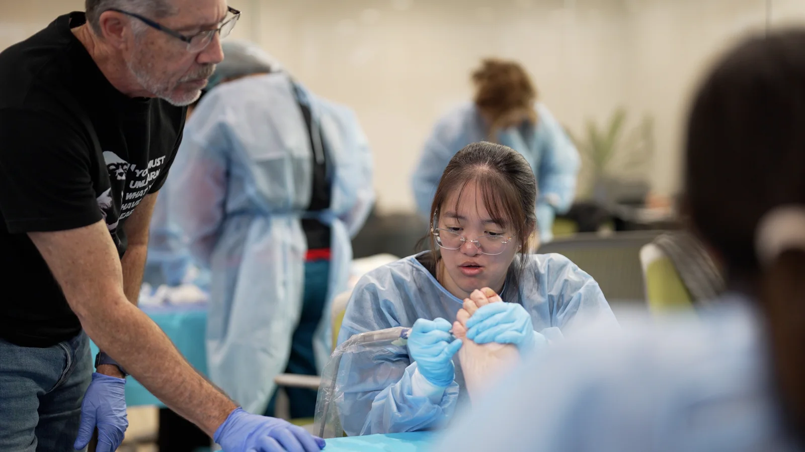 A surgeon practicing at a cadaver station with a faculty member nearby